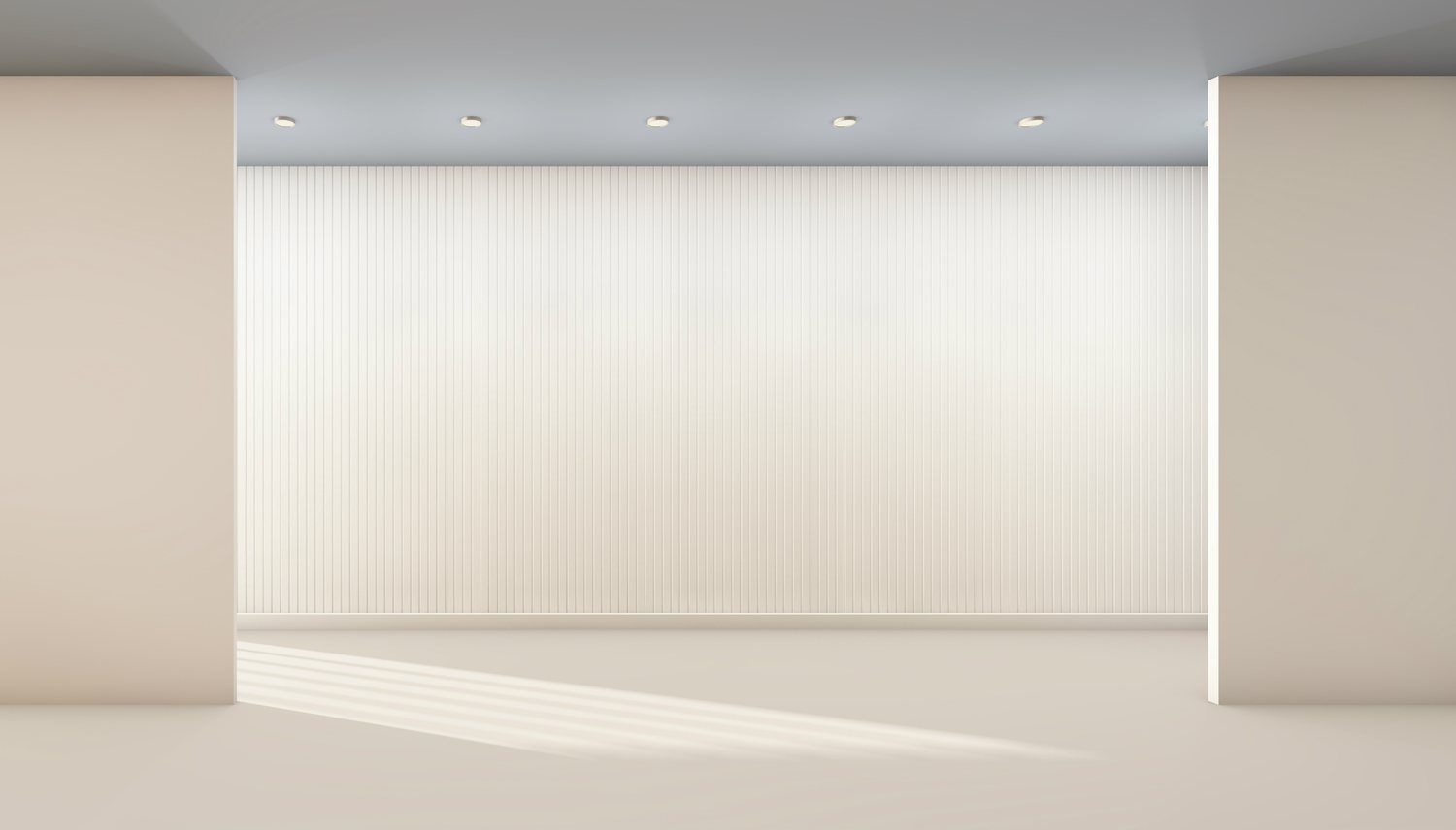 Sala de galería vacía, con un banco claro y la pared del fondo libre bajo sus focos